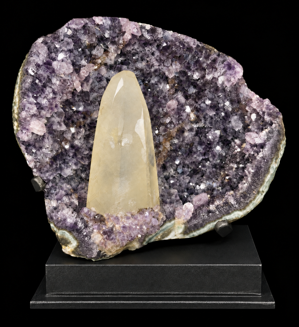 A statement amethyst geode display with a prominent ivory calcite crystal point set inside a purple amethyst cavity, mounted on a black display stand.