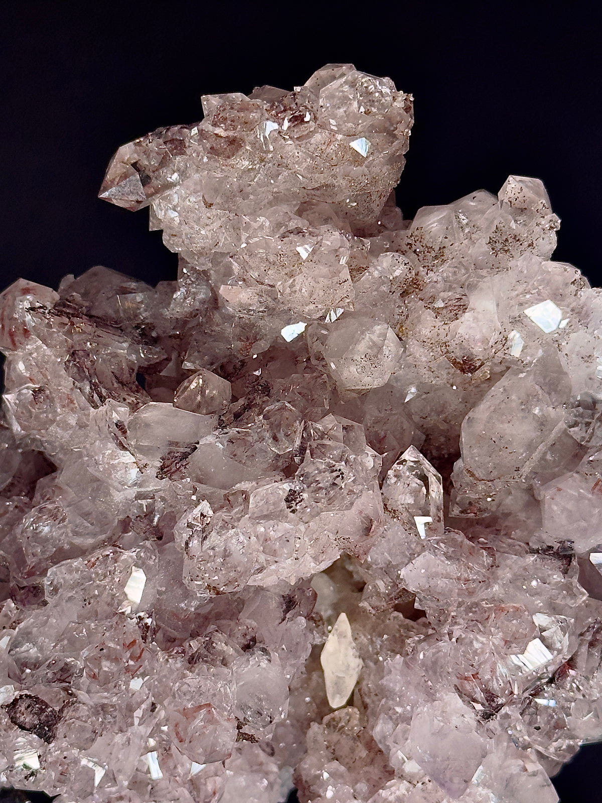 A cluster of pale pinkish-lavender quartz amethyst crystal points with goethite and calcite — natural mineral specimen.