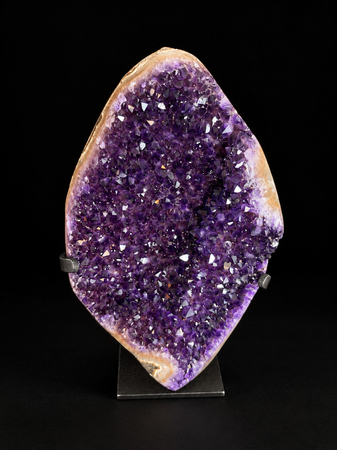 A large amethyst geode specimen with a purple crystal interior and tan outer matrix.