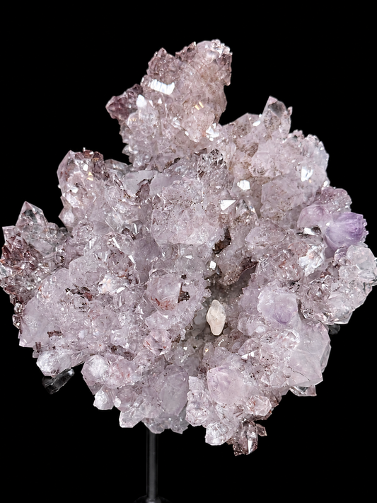 A cluster of pale pinkish-lavender quartz amethyst crystal points with a calcite crystal mounted on a black display stand.