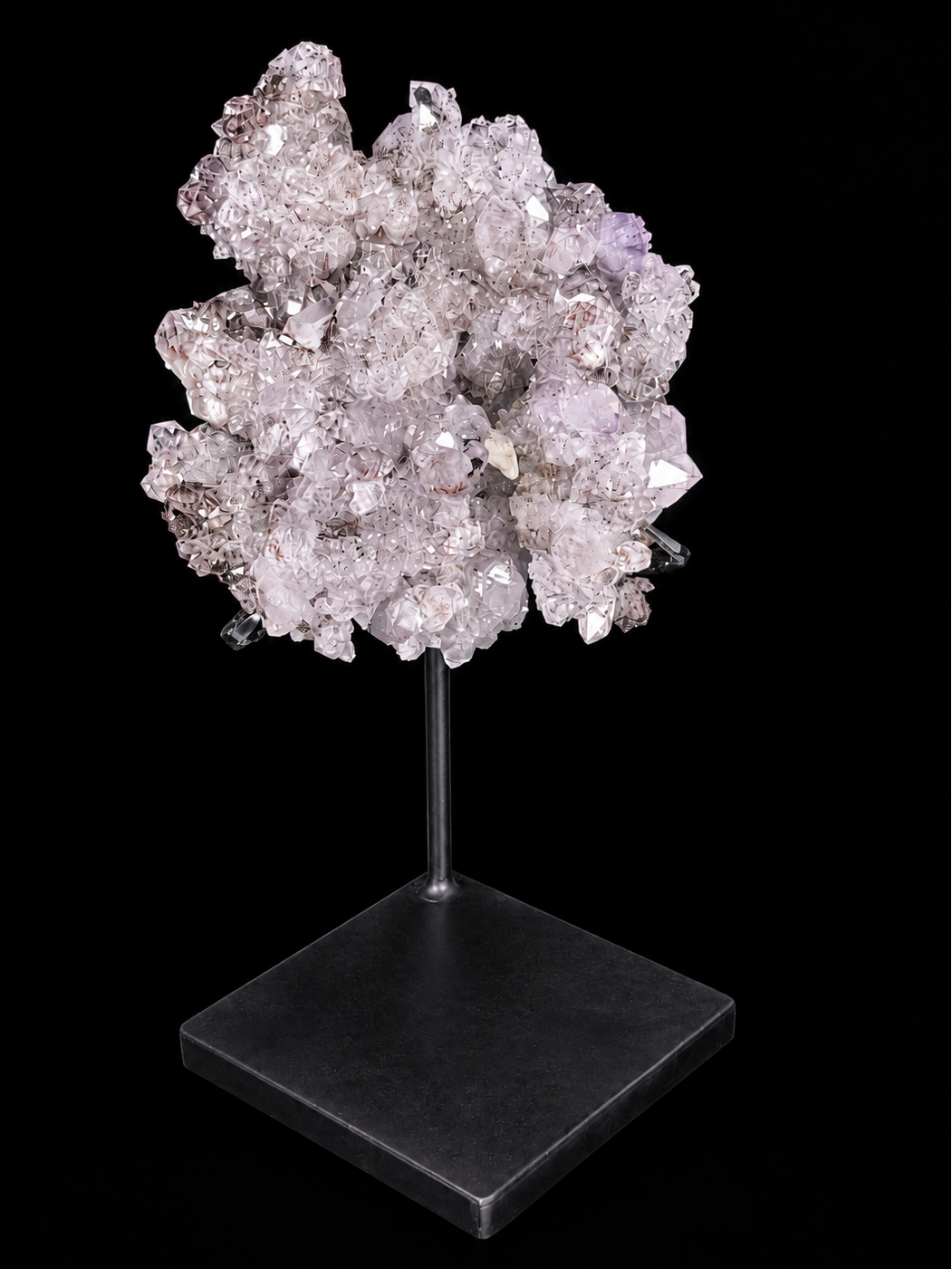 Pale pinkish-lavender amethyst crystal points with a calcite crystal on a black display stand — one-of-a-kind home decor.