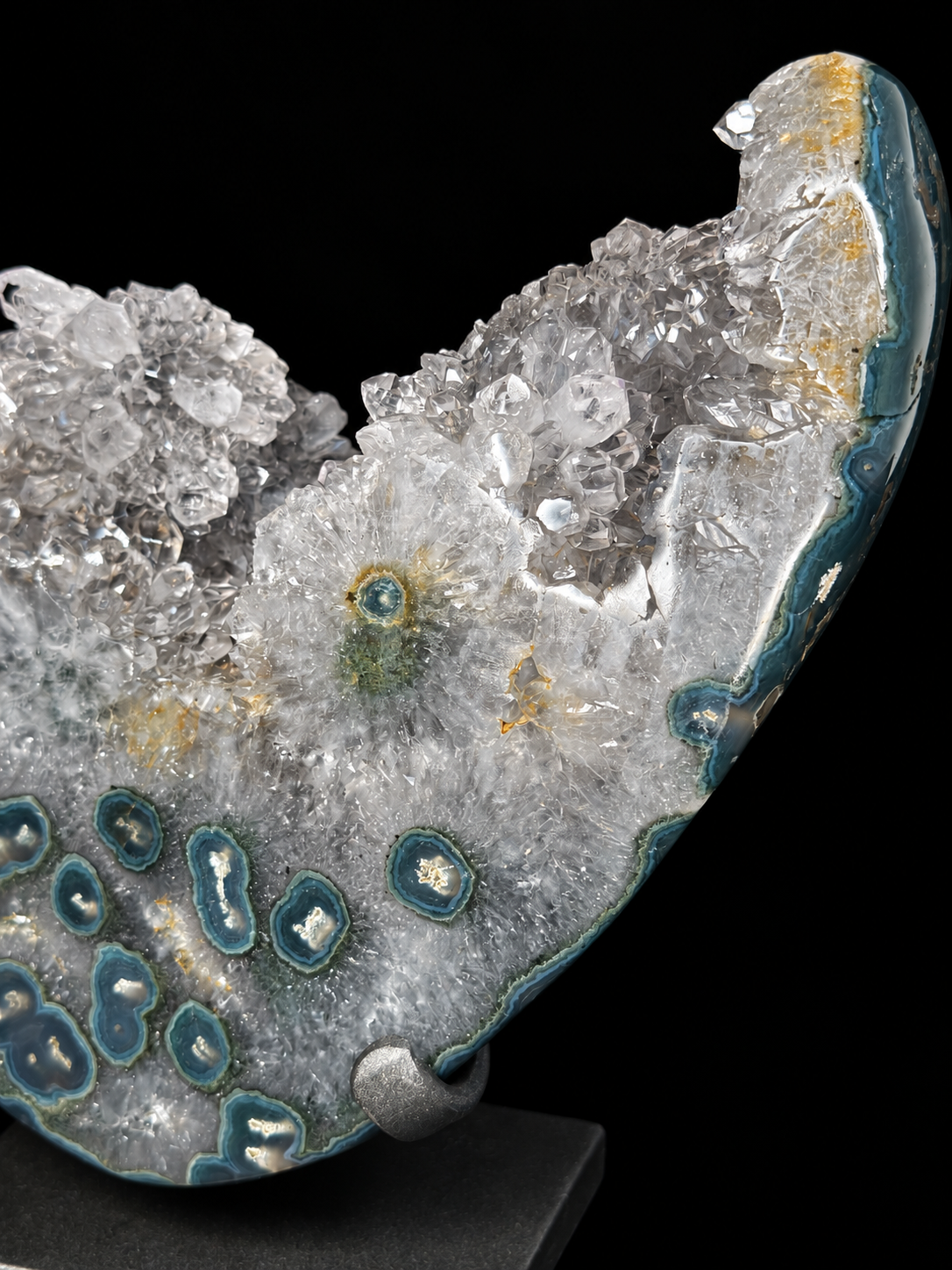 A polished crystal quartz agate specimen with clear quartz clusters and blue-green agate matrix, mounted on a small display stand against a black background.