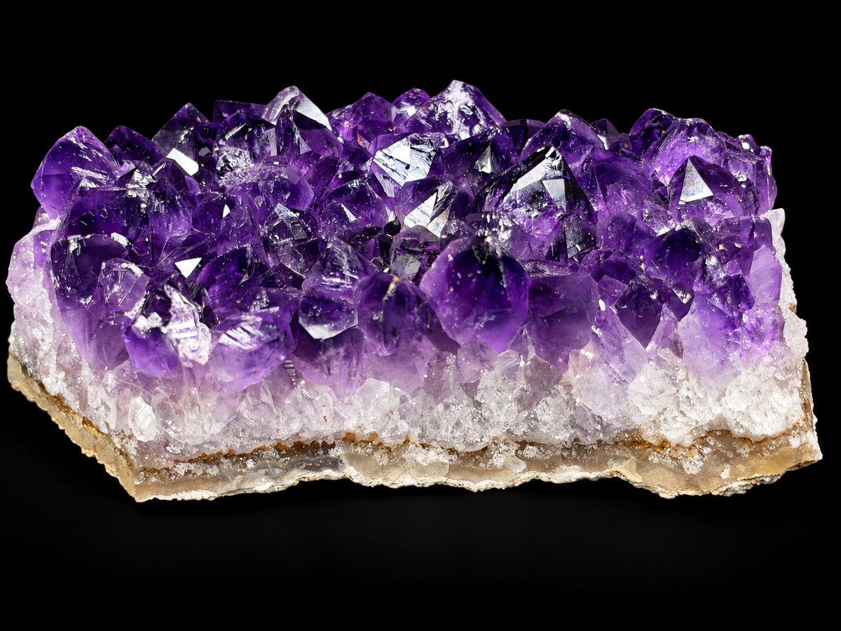 A natural amethyst crystal cluster specimen with purple quartz points rising from a tan matrix.