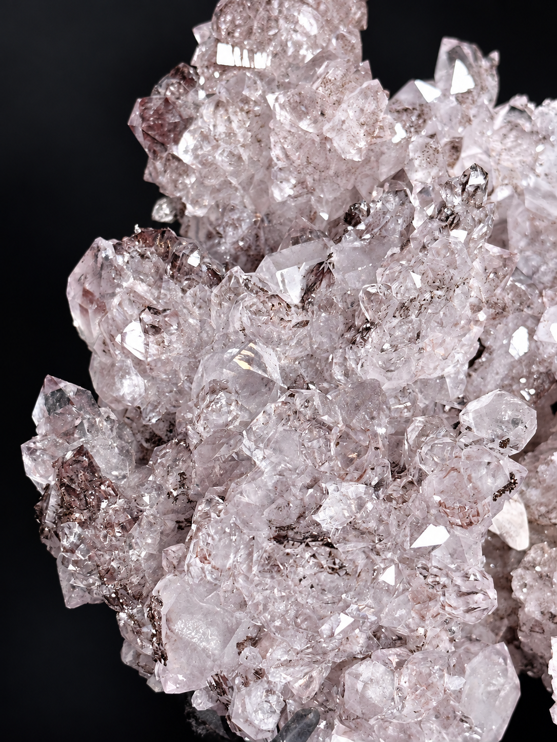 Pale pinkish-lavender quartz amethyst crystal points with calcite on a black display stand — natural crystal home decor.